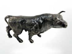 A metal figure of a bull on marble plinth.