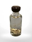 A glass bottle containing fine gold leaf fragments suspended in liquid.