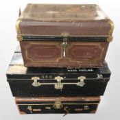 Two lacquered tin trunks and a further leather example,