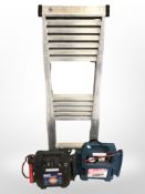A telescopic ladder, together with two battery jumpstarters.