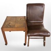 A brown vinyl bedroom chair together with a tiled occasional table.