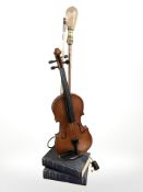 A contemporary table lamp in the form of a violin on a stack of books.