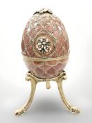 An enameled musical Fabergé-style egg on gilt metal stand.