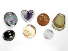 A group of seven coloured glass paperweights.