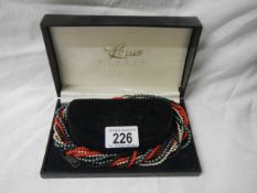 A boxed multi coloured necklace.