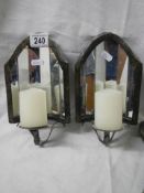 A pair of wall mounting candle holders with mirrors in back.