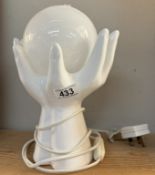 A white glazed pottery pair of hands holding spherical glass shade table lamp. In working order