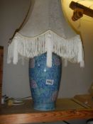 A good blue ceramic table lamp with fringed shade, COLLECT ONLY.