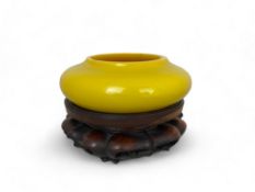 A late 19th century Chinese yellow Peking glass bowl on hardwood lobed stand
