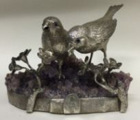 A pair of silver figures of birds on amethyst base.