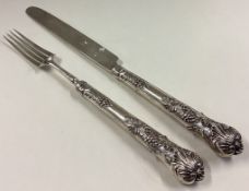 A William IV silver knife and fork with crested terminals decorated with grapes and vines.
