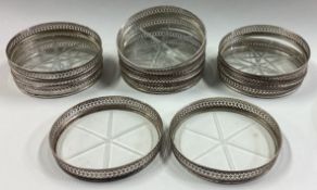 A set of twelve silver bottle coasters with glass bottoms.