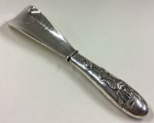 A Japanese silver shoe horn decorated with chased rose water lilies to handle.