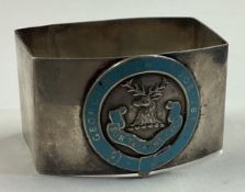 A silver and enamelled napkin ring with chased decoration of a stag to centre.