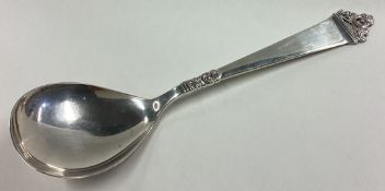 A stylish silver spoon with scroll decoration.