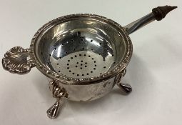 A heavy modern silver tea strainer on stand.