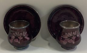 A pair of Asian silver and purple enamelled shot cups on matching saucers.