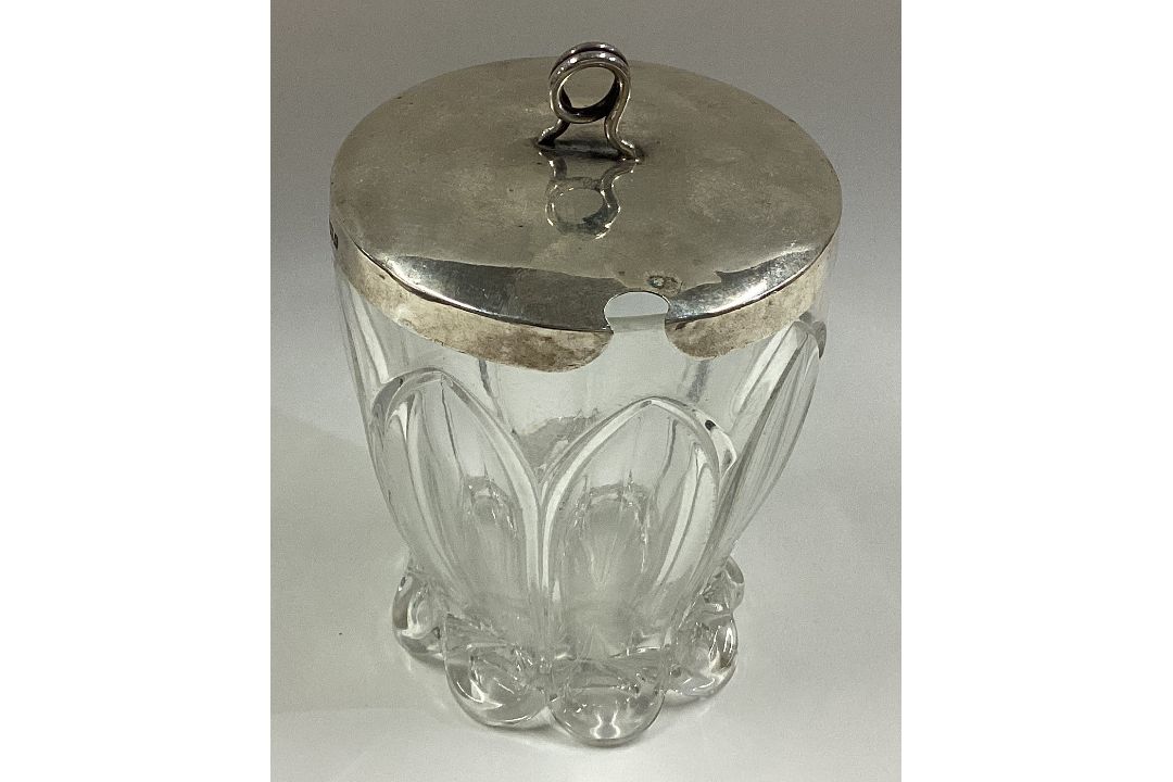 A silver and glass honey jar.