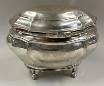 A silver tea caddy on four feet with hinged lid.