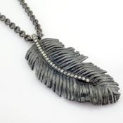 An exquisite feather necklace detailed with brilliant diamonds and gold on silver.