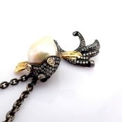 A bird necklace detailed with baroque pearl .brilliant diamonds and gold on silver.