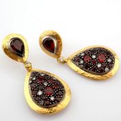 An exquisite earrings detailed with red garnets , brilliant diamonds and gold in silver