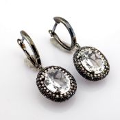 An exquisite earrings detailed with white topaz, brilliant diamonds and gold in black rhodium