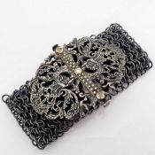 A handwoven silver bracelet adorned with gold and precious stones