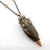 An exquisite ebony-carved owl necklace detailed with brilliant diamonds and gold on silver.
