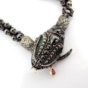 An exquisite snake necklace intricately detailed with skulls on chain. Brilliant diamonds in silver.