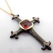 An exquisite cross necklace detailed with red garnet, brilliant diamonds and gold on silver