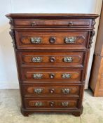 An oak chest of drawers with five standard drawers, a glove drawer and ornate brass drop handles (