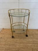 A glass and brass effect drinks trolly with galleried top (H60cm Dia38cm)