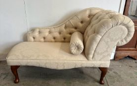 A small button back chaise lounge, upholstered in a cream floral pattern