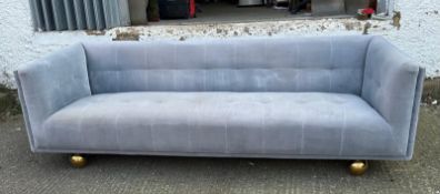 A contemporary four seater upholstered sofa in grey on brass ball feet 230cm x 86cm