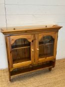 A wall hanging pine unit with glazed doors (H90cm W83cm D20cm)