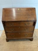 An oak three drawer bureau with brass drop handles. The fall opening to reveal three drawers and