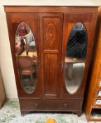 A mahogany and inlaid wardrobe comprising of two mirrored doors flanking an ornate central shield