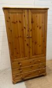 A pine two door wardrobe with three drawers under (H157cm W84cm D52cm)