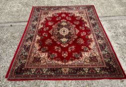 A large red and beige rug with central medallion encompassed by floral groups 280cm x 202cm