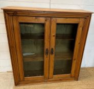 A distressed pine two door glazed cabinet opening to two shelves (H92cm D32cm W90cm)