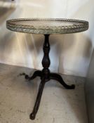 A circular oak pedestal table with galleried brass top on cast iron splayed legs
