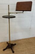 A vintage music stand with brass central column and adjustable arm on cast iron lions paw feet