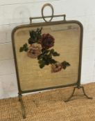 An Art Nouveau brass framed fire screen with a painted floral mirrored panel