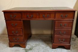 A green leather topped pedestal desk, a long central drawer flanked by four short drawers and a