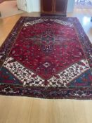 A red ground rug with central shield and a blue and red boarder
