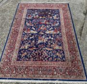 A blue ground rug in reds and browns depicting a hunting scene 243x170