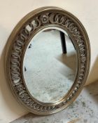 An oval wooden gold painted wall mirror with an inter locking circular border