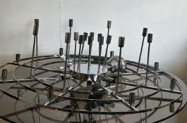 A substantial circular chrome ceiling light with multiple drop and side facing light fittings (