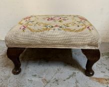 A floral upholstered foot stool on cabriole legs